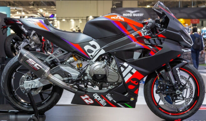 Aprilia RS 457 Trofeo 2025 con scarico SC Project, livrea ufficiale racing e grafiche Aprilia. Moto esposta in fiera per noleggio pista