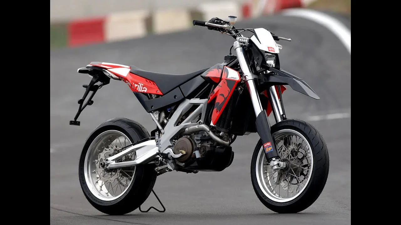 Red and black Aprilia SXV550 supermoto motorcycle on track with street tires and disc brakes