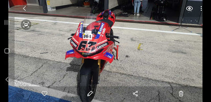 Vista frontale Ducati Panigale V4S 2025 replica MotoGP con livrea Lenovo parcheggiata davanti al box
